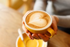 lady's hands hold cup filled with something heart-shaped