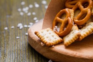 Selection of salty snacks, wood background, closeup